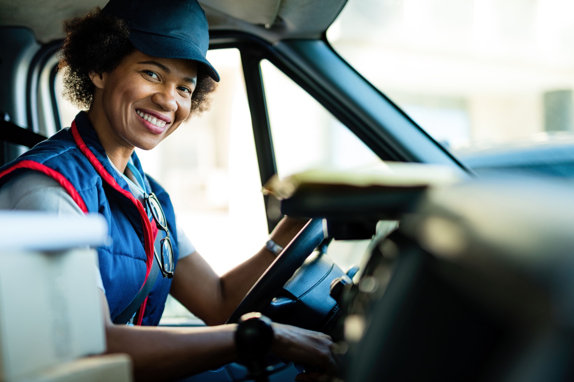 Happy African American delivery woman driving a van.